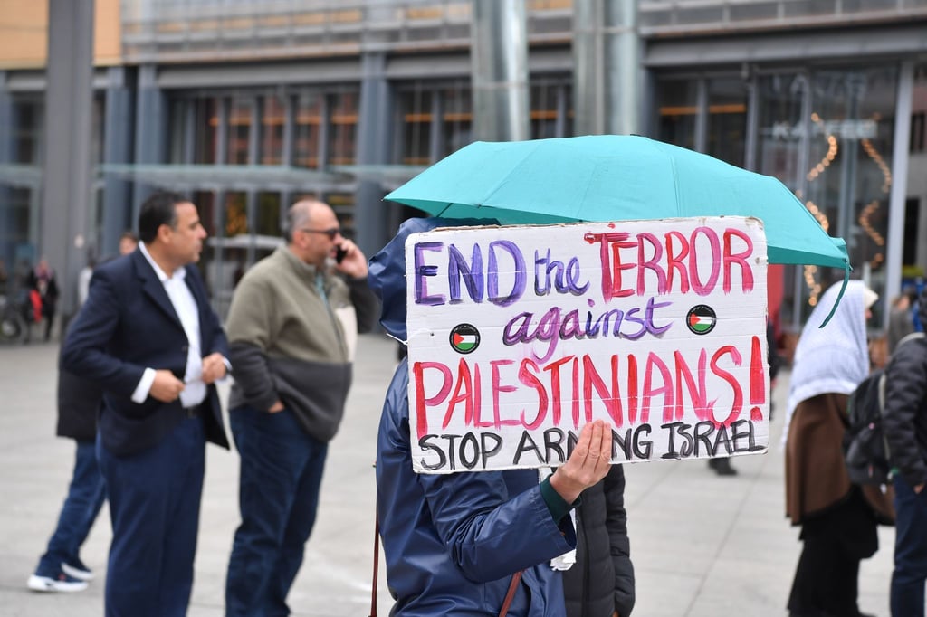 Eine Demonstrantin hält bei einer Propalästinensischen Demonstration auf dem Potsdamer Platz ein Schild hoch.