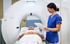 Eine Mitarbeiterin der Helios-Klinik bespricht mit einem Patienten eine bevorstehende Untersuchung im Computertomografen. 