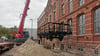 Ein Schwerlastkran hebt den ersten von vier Güterwagen auf das Gleis vor der ehemaligen Backwarenfabrik in Magdeburg. hier entstehen neue Wohnungen mit ganz besonderen Extras.