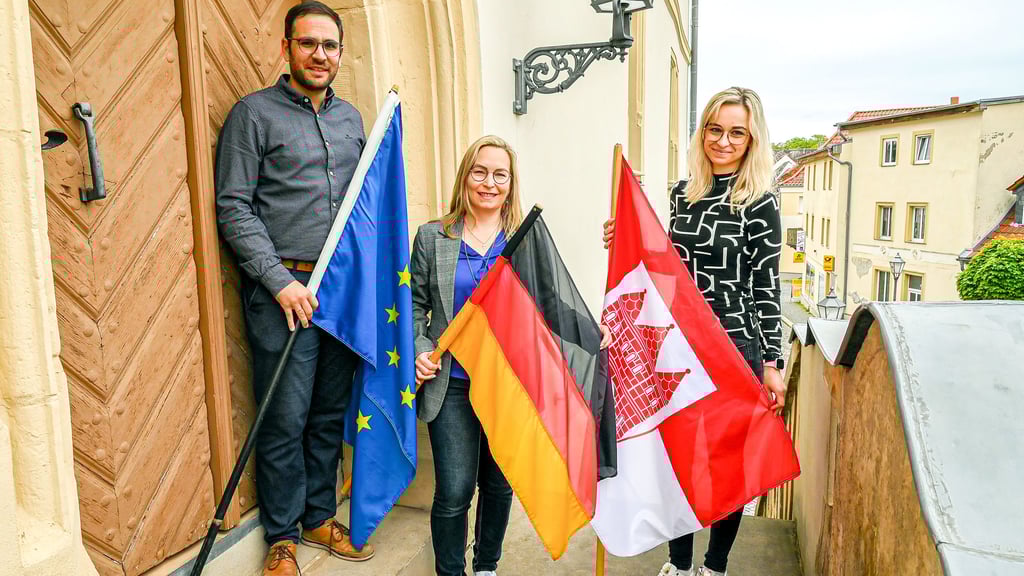 Christian Filly, Bürgermeisterin Grit Matz (Mitte) und Michelle-Isabelle Hochsieder bereiten die Fahnen am Rathaus vor.
