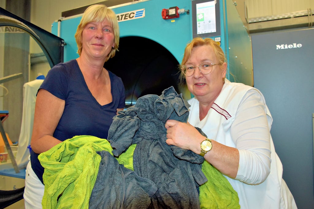 In der Wäscherei Am Güterbahnhof in Zeitz gibt es drei Waschmaschinen mit einer Füllmenge von 60 Kilogramm und eine mit 16 Kilogramm. Manuela Holzhauer (li.) und Marina Böttcher (re.) füllen Handtücher in einen der fünf Trockner. Eng ist es in der Halle geworden. Deshalb wird zurzeit angebaut.