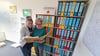 Silke Piel (r.) und Ellen Steinhorst vom DRK-Suchdienst Sachsen-Anhalt vor einem Regal mit Fallakten.