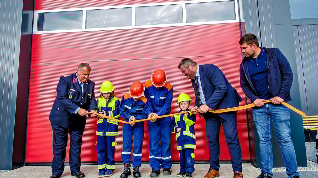 Die Kinder und Jugendlichen öffnen symbolisch die neue Halle. Wehrleiter Steffen Pluhm-Jude, die Bürgermeister Enrico Schilling und Paul Kreibich helfen.