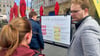 FDP-Stadtrat Tim Kehrwieder (r.) fragt Bürger auf dem Marktplatz nach ihren Sparvorschlägen für den Stadthaushalt.