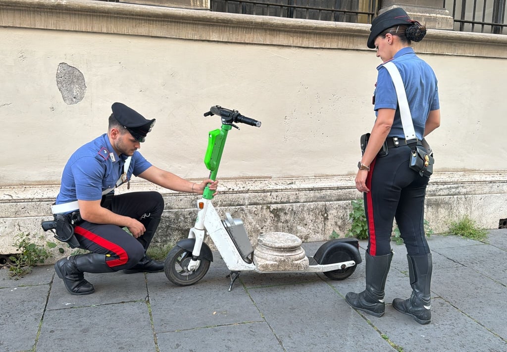 Zwei Carabinieri begutachten den Marmorsockel auf einem elektrischen Leihroller.