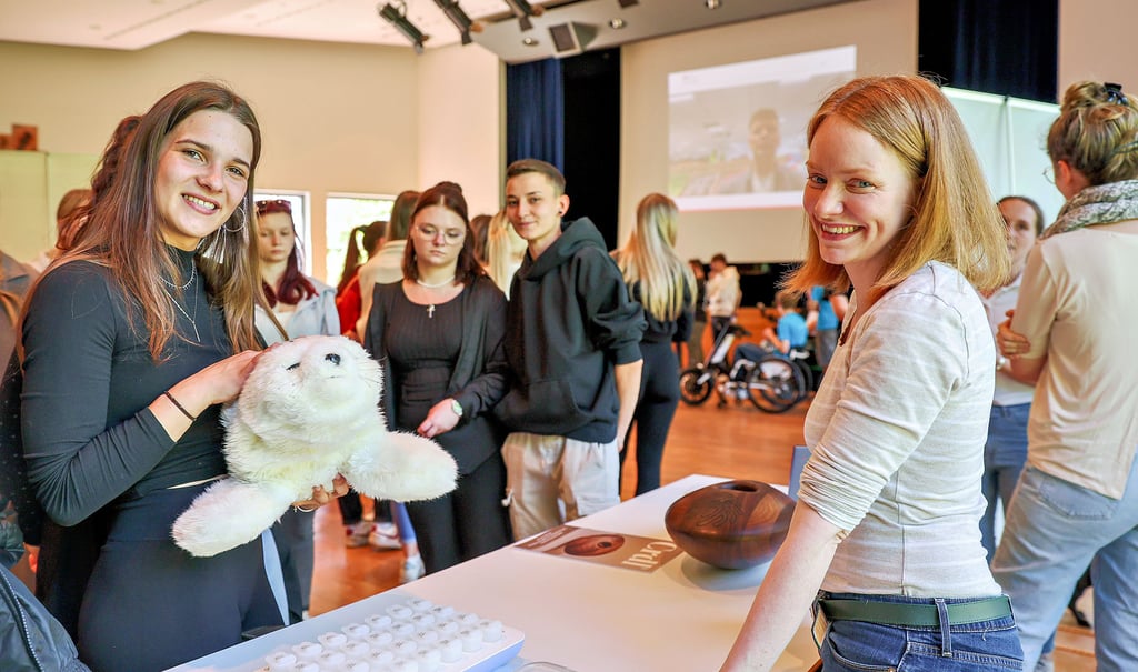 Lilly Soe Reinhardt aus Weißenfels (l.) macht eine Ausbildung zur Pflegefachfrau bei der Arbeiterwohlfahrt und lässt sich die „Demenzrobbe“ von Kirsten Neumann von der Uni Halle erklären.