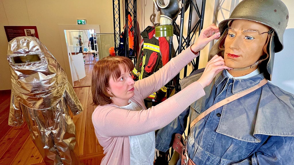 Museumsleiterin Christiane Heinevetter richtet den Stahlhelm der Einsatzkleidung.