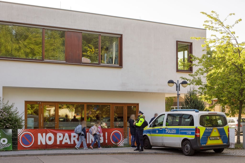 Die Polizei steht vor einer Grundschule im Berliner Bezirk Spandau, während Schüler am Morgen zur Schule kommen.