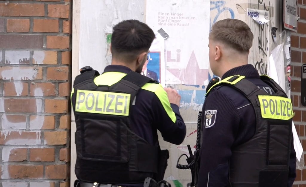 Zwei Polizisten entfernen ein Plakat, das den am Mittwoch erschossenen Deutsch-Israeli Yaron Lischinsky zeigt.