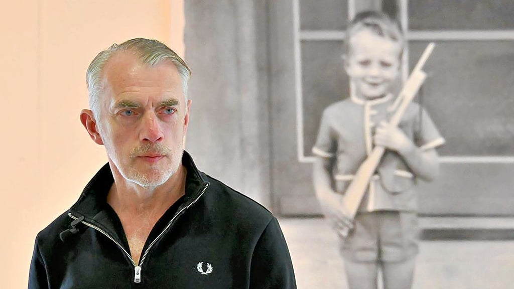 Zwei Künstlerkollegen: Neo Rauch im Eingangsbereich der Neo Rauch Stiftung in Aschersleben vor einem Foto des kleinen Neo aus Kindertagen.