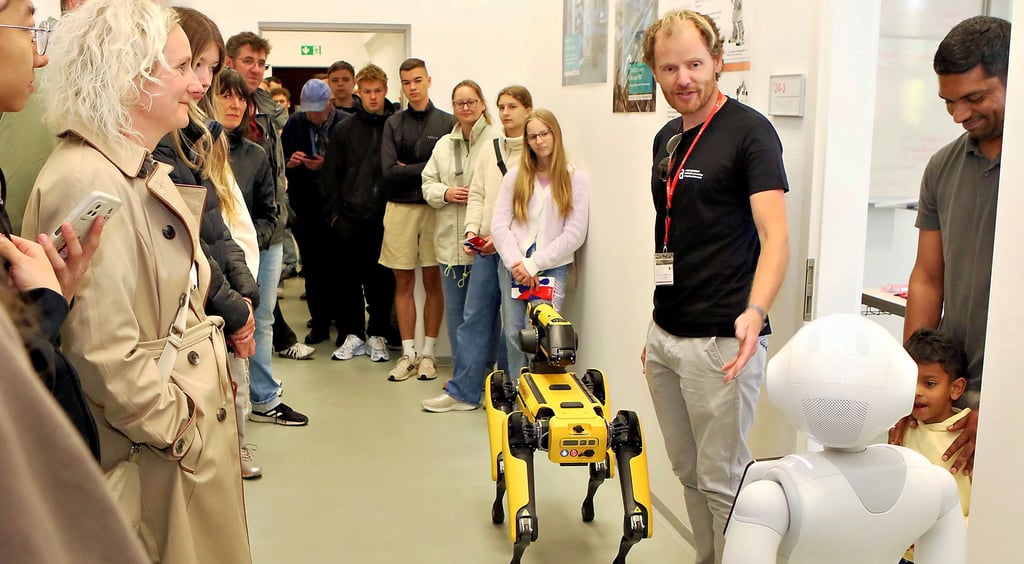 Professor Stefan Twieg stellt den Besuchern einen Roboterhund und einen humanoiden Roboter vor.
