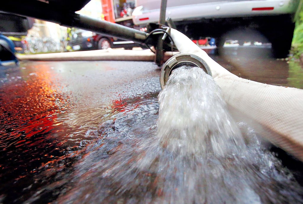 Feuerwehrleute pumpen Wasser aus einem Keller.