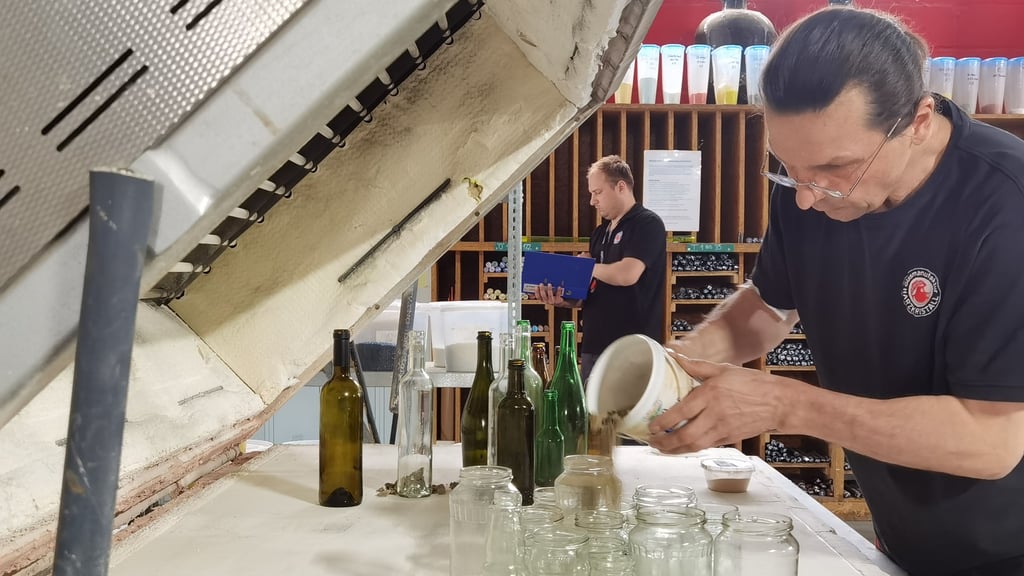 Hüttenmeister René Jacksch füllt Sand zwischen Glasflaschen. Das Material soll im Rahmen einer Kunstinstallation im Fusing-Ofen der Glasmanufaktur "Harzkristall" in Derenburg bei mehr als 800 Grad ineinander verschmelzen.