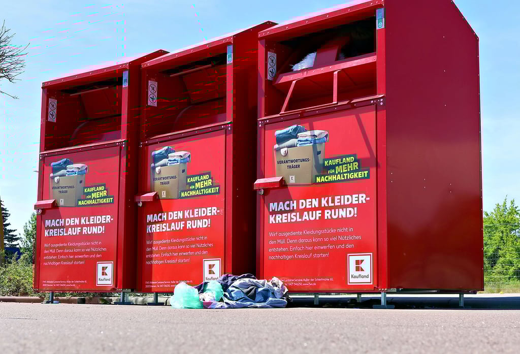 Die Klappen der von FWS betriebenen Altkleidercontainer am Kaufland-Markt in Köthen sind geteilt, was als Schutz gegen den Einstieg dienen soll. Auch hier liegt jedoch Unrat davor. Die Klappen der bunten Container unten im Bild seien leicht zu umgehen und begünstigten Diebstähle, so die FWS.