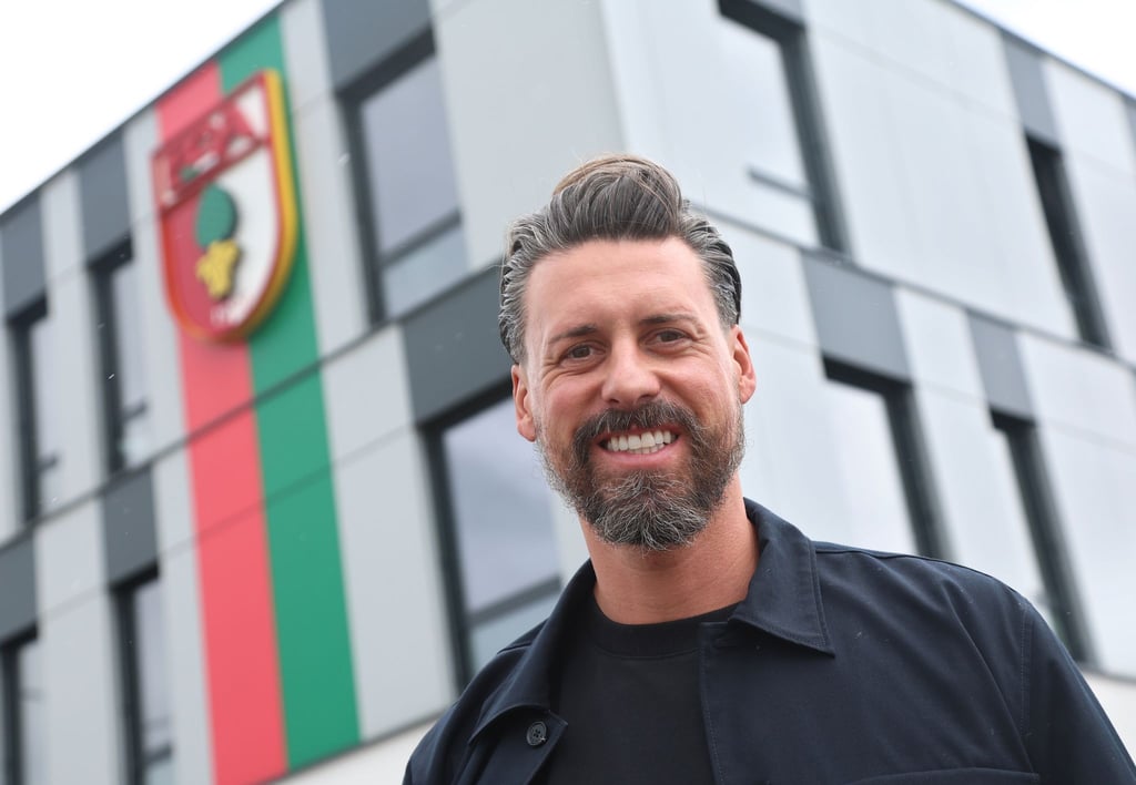 Der neue Trainer Sandro Wagner posiert vor der Geschäftsstelle des FC Augsburg.
