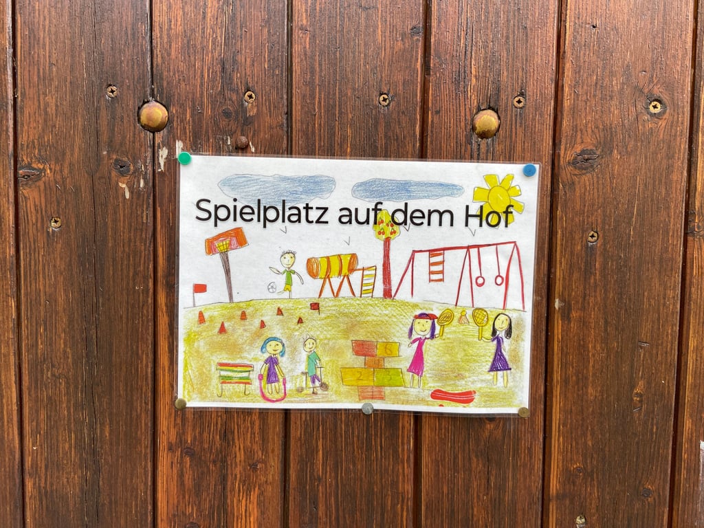 Ein Schild am Tor neben dem Bürgerhaus in Magdeburg-Calenberge weist darauf hin, dass sich hinter dem Eingang ein Spielplatz befindet – doch das reicht nicht, um Kinder auf die Spielmöglichkeit aufmerksam zu machen.