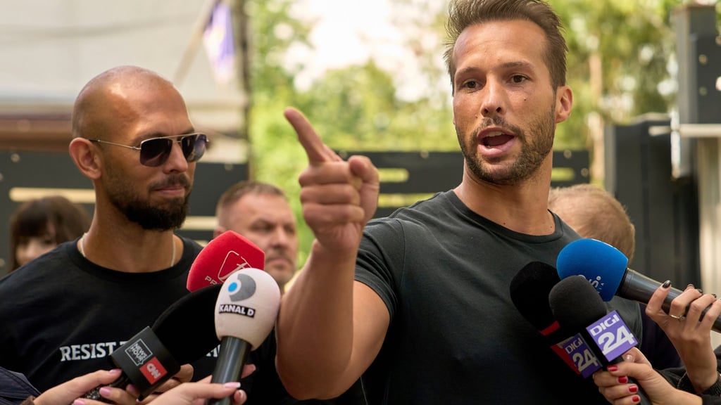 Andrew Tate (links) schaut zu seinem Bruder Tristan Tate, der am 21. Mai vor einer Polizeistation in Voluntari in Rumänien redete.