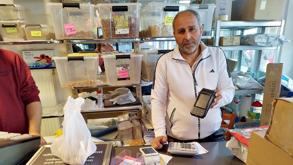 Kasim al Dagher, Inhaber des Sultanmarktes in der Breiten Straße in Salzwedel, mit dem Kartenlesegerät, das die Bezahlkarte in seinem Geschäft akzeptiert.
