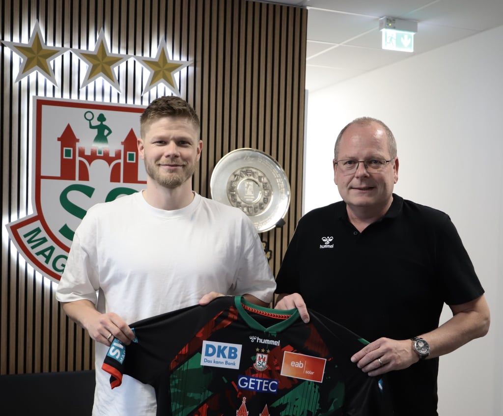 Sebastian Barthold zeigt zusammen mit SCM-Geschäftsführer Marc-Henrik Schmedt, für welchen Verein er nächste Saison spielen wird.