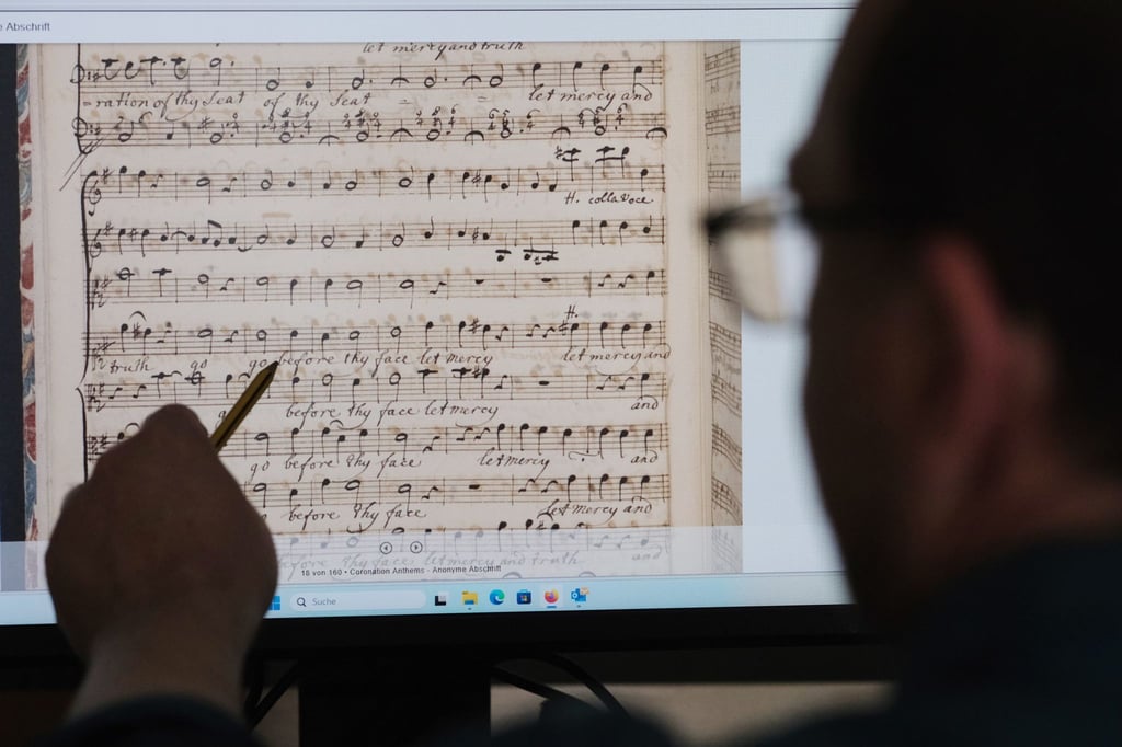 Jens Wehmann, Bibliothekar des Händelhauses, sitzt vor Scans von Partituren der Krönungshymnen von Georg-Friedrich Händel.