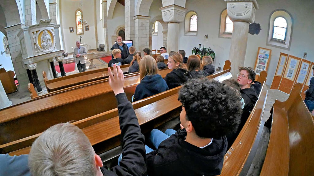 Rüdiger Kempe vom Gemeindekirchenrat zeigt den Schülern die Kirche.