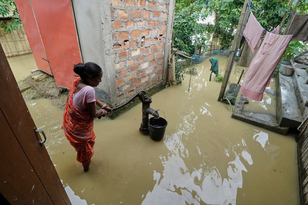 Eine Frau versucht in der überfluteten Umgebung ihres Hauses, Wasser zu sammeln.