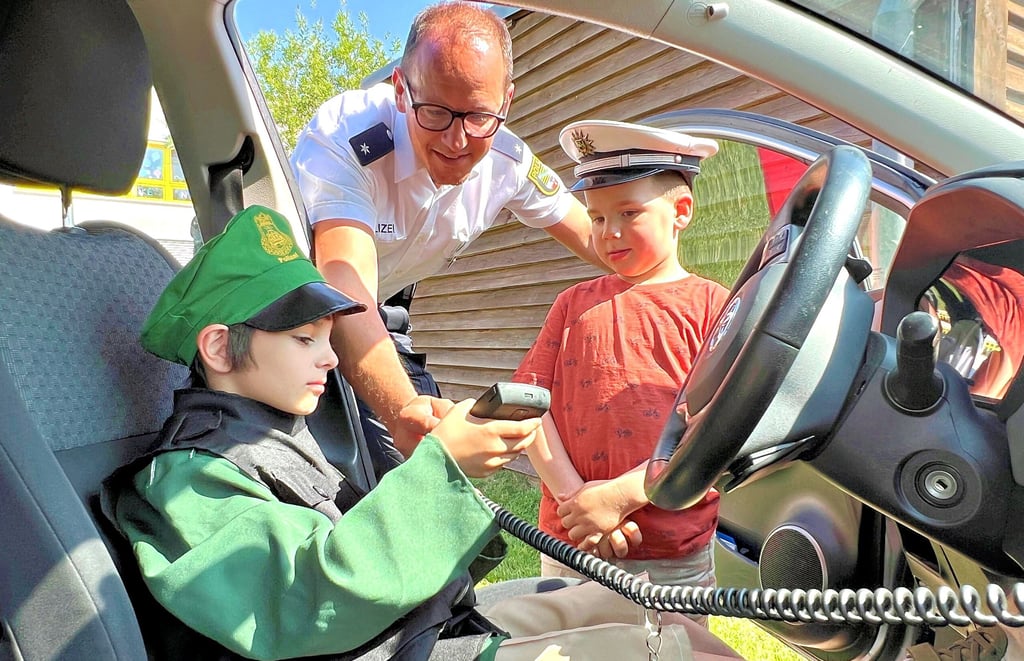 Polizeikommissar Sebastian Montag erklärte den beiden Sechsjährigen Tobias (l.) und Lenny, das Funkgerät im Polizeiauto.