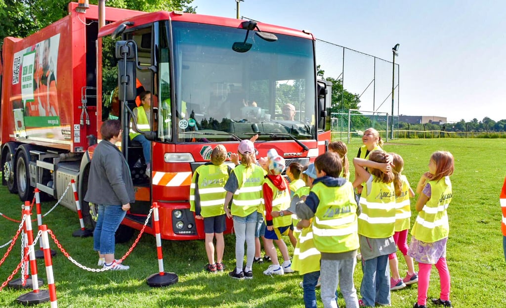 Osterfelder Grundschüler stellen sich vor ein Müllfahrzeug, um zu testen, ob sie aus dem Cockpit des Fahrzeuges gesehen werden.