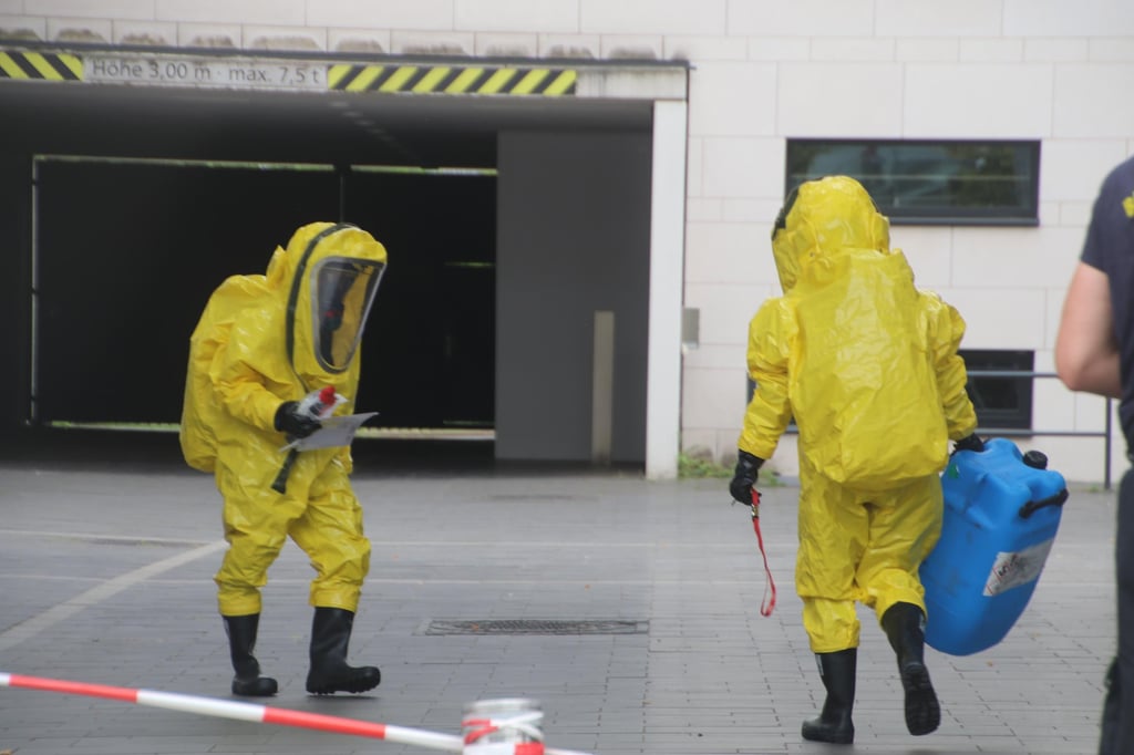 Einsatzkräfte betreten mit Schutzanzügen den Raum.