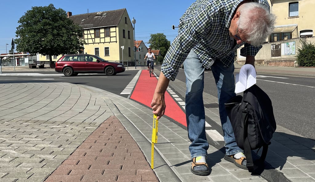 Die neue Kreuzung am Bahnhof in Tangerhütte: Wer hier im spitzen Winkel über den Bordstein fährt, der rutscht schnell mal weg. Verkehrsfachmann Werner Hartig misst nach - nicht nur der Bordstein ist höher als er sein sollte, auch das rote Pflaster bildet noch einmal eine Kante von einigen Millimetern.