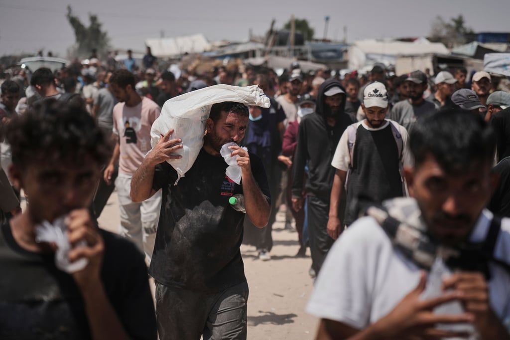 Ein Palästinenser trägt am 6. Juni 2025 zwischen anderen Hilesuchenden einen Sack mit humanitären Hilfsgütern in Rafah im Gazastreifen.