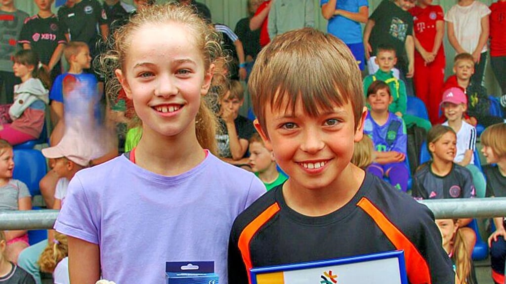 Leonie Beyer und Konrad Keller aus der Klassenstufe 4 präsentieren stellvertretend für die Schülerschaft die Urkunde.