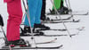 Skifahrer stehen in einer Reihe an der Piste.
