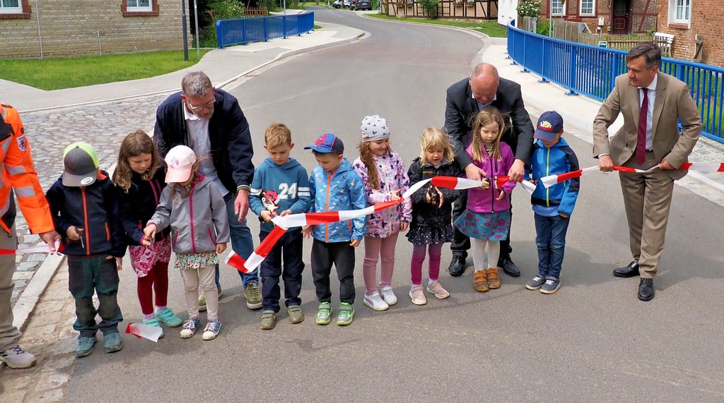 Mit Hilfe von Ortsbürgermeister Jörg-Andreas Altenburg, Bürgermeister Dirk Heinemann und Landrat Thomas Balcerowski (von links) gaben die Knirpse aus dem Kindergarten die nagelneue Eckergrabenbrücke offiziell frei.