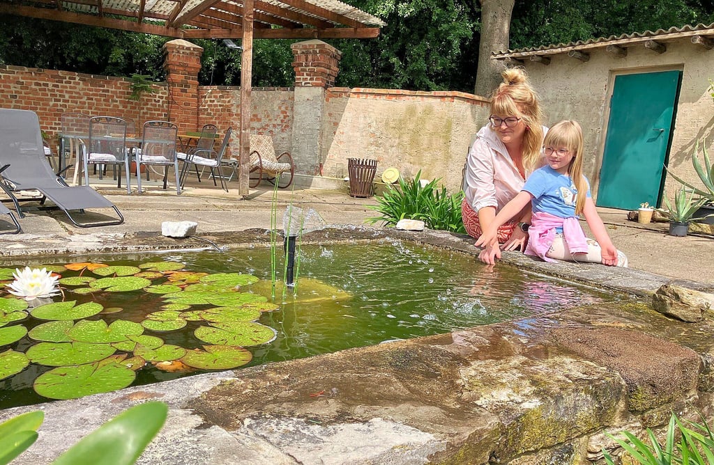 Katja und Lotta Rieger sitzen am Rand des Teiches von Familie Schütze.