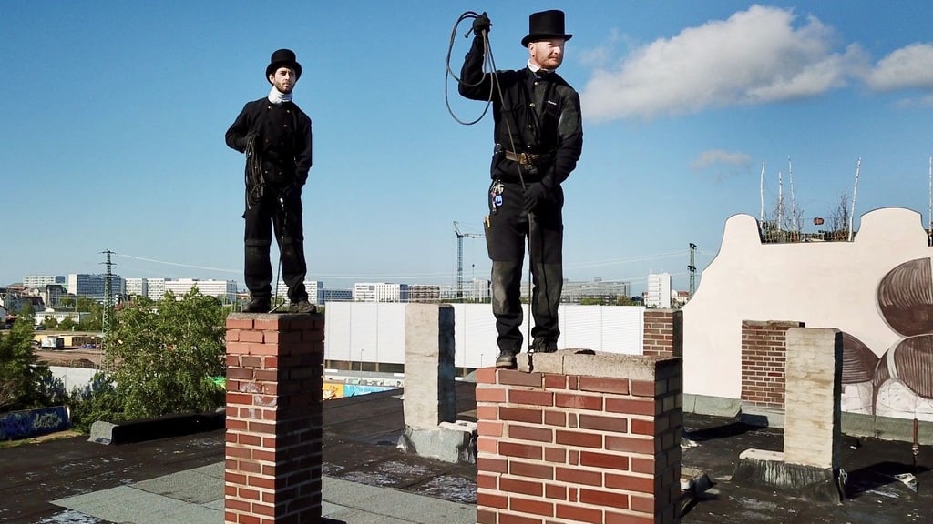 Zwei Schornsteinfeger gehen in der Landsberger Straße artistisch ihrem Beruf nach. Die schwarzen Männer gelten als Glücksbringer.