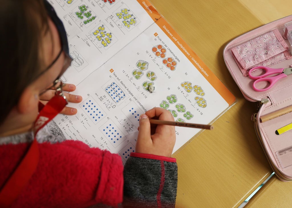 Eine Schülerin schreibt im Unterricht in ihr Schulbuch und löst eine Rechenaufgabe. Allein für die Arbeitshefte sind die jährlichen Kosten enorm.