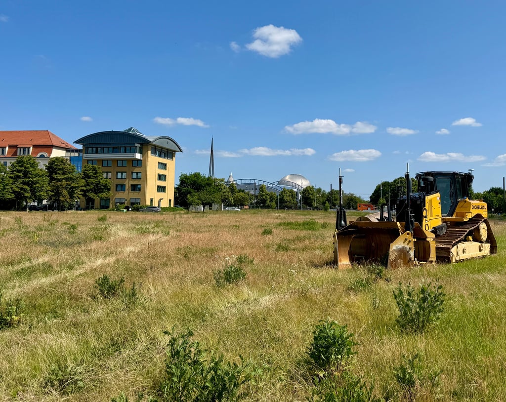 Eine erste Baumaschine steht bereits auf der Grünfläche.