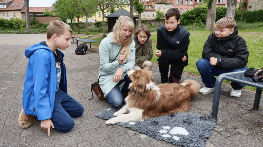 Christina Schneppe (2.v.li.) zeigt mit Cooper wie man Hunden eindeutige Befehle gibt. Pascale (li.) sowie Andrea, Oscar und Franz lernen in der Schulhund-AG viel über den Umgang mit den Vierbeinern.