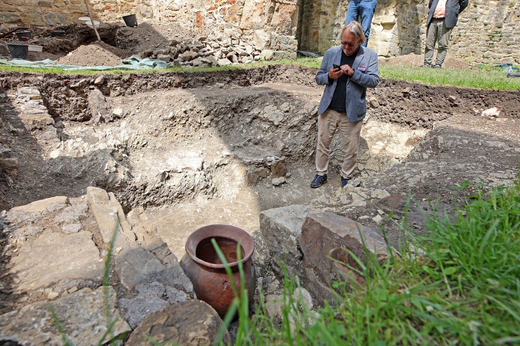 Landesarchäologe Harald Meller vom Landesamt für Denkmalpflege und Archäologie Sachsen-Anhalt zeigt wie ein Krug (vorne) in der Grabstelle in der Ruine der Stiftskirche St. Marien in Walbeck gestanden hat.