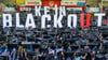 Leag-Beschäftigte halten bei einer Betriebsversammlung im Fußballstadion in Cottbus den Spruch „Kein Blackout“ hoch.