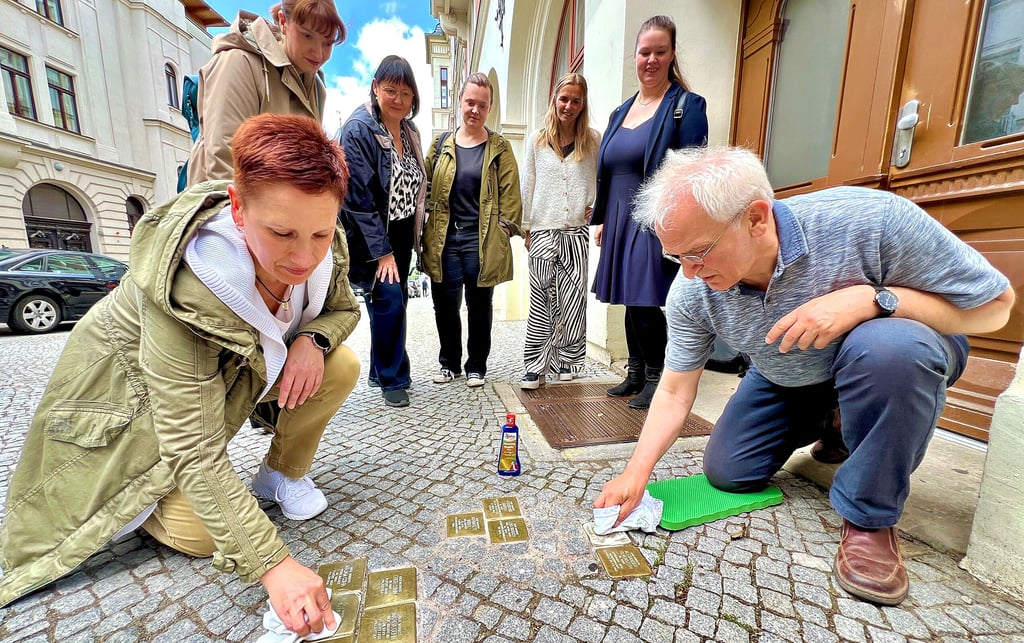 Claudia Schöne und Joachim Grossert polieren die neun Stolpersteine, die vor dem Haus Wilhelmstraße 1 verlegt sind, auf Hochglanz. Auch Christiane Heinevetter (stehend von links), Kerstin Schmidt, Judith Gebauer, Alexandra Stöhr und Anett Gottschalk engagieren sich für den Arbeitskreis „Jüdische Geschichte in Bernburg“.