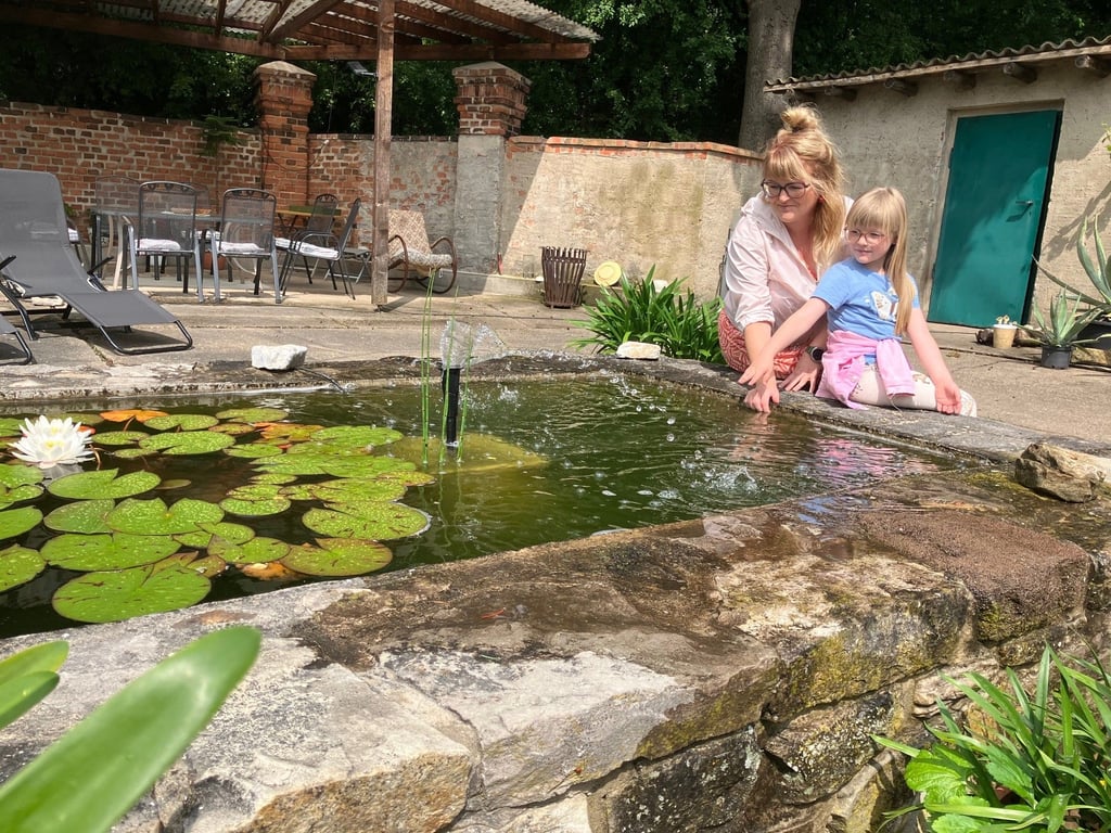 Katja und Lotta Rieger sitzen am Rand des Teiches von Familie Schütze