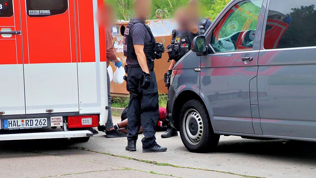 Ein Mann liegt in Halle-Neustadt auf dem Boden und wird von Polizisten umstellt. Er sollte mutmaßlich in sein Heimatland abgeschoben werden.