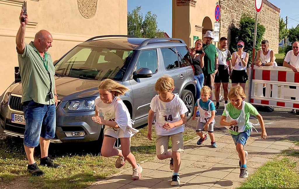 Aderstedts Ortsbürgermeister Mike Franzelius gibt den Startschuss für den Kinderwettbewerb beim Strengelauf.