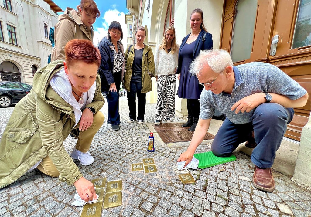 Claudia Schöne und Joachim Grossert polieren die neun Stolpersteine, die vor dem Haus Wilhelmstraße 1 verlegt sind, auf Hochglanz. Auch Christiane Heinevetter (stehend von links), Kerstin Schmidt, Judith Gebauer, Alexandra Stöhr und Anett Gottschalk engagieren sich für den Arbeitskreis „Jüdische Geschichte in Bernburg“.