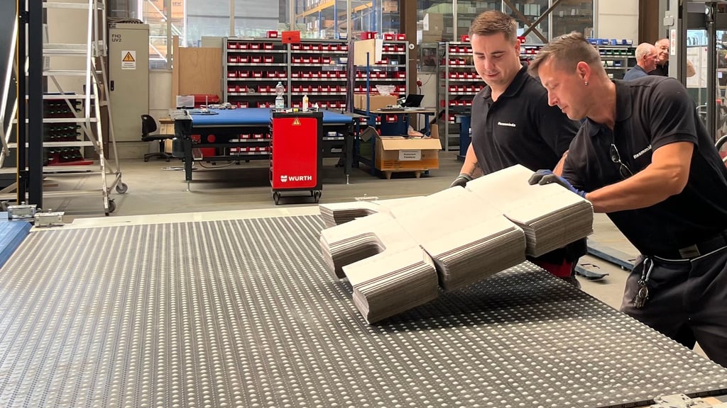 Tobias Hausner (links) und Dominique Halbas sind Mitarbeiter bei Minda Industrieanlagen in Tangermünde und bestücken ein Laufband im Probelauf mit Pappe. Sie testen, ob die Anlage genau das tut, was sie beim Kunden in wenigen Tagen täglich leisten soll.