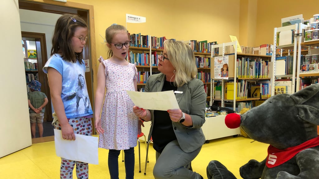 In der Kinderbibliothek in Quedlinburg erklären Alva (M.) und Holly (l.) Isabel Jahnsmüller, was auf ihren Bildern zu sehen ist.