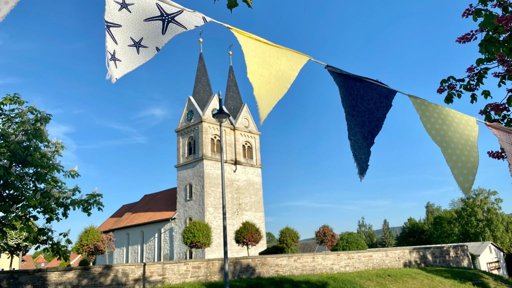 Eine bunte Wimpelkette zieht sich durch Minsleben zum 1.025-jährigen Jubiläum des Dorfes bei Wernigerode - auch an der Kirche St. Margareten entlang.