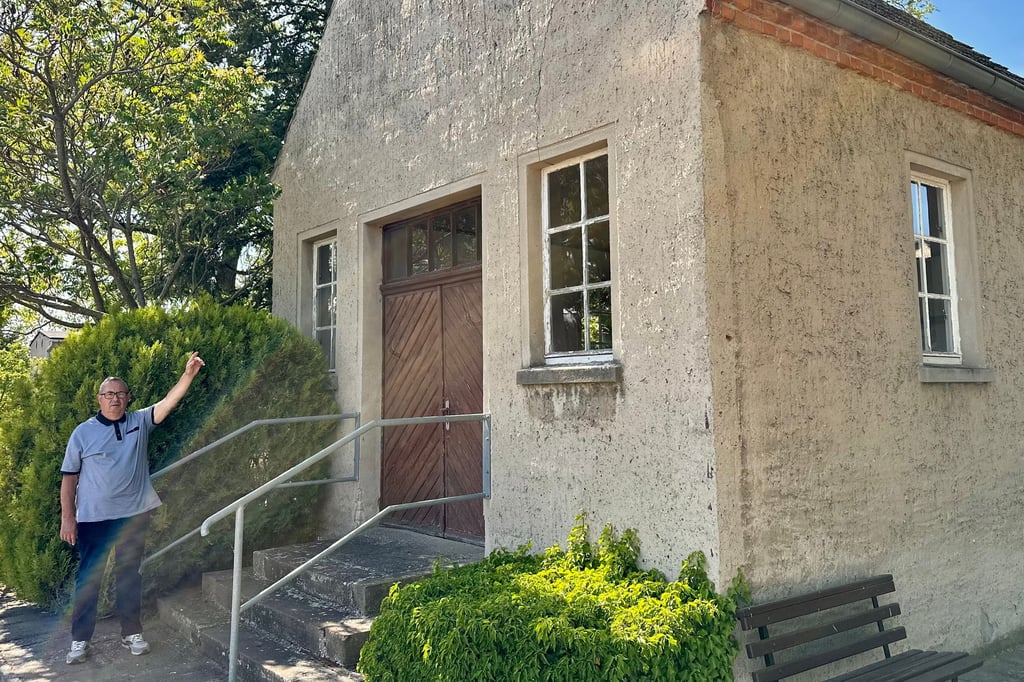 Reesens Ortsbürgermeister Otto Voigt zeigt auf die Trauerhalle im Dorf, die sich in einem desolaten Zustand befindet.